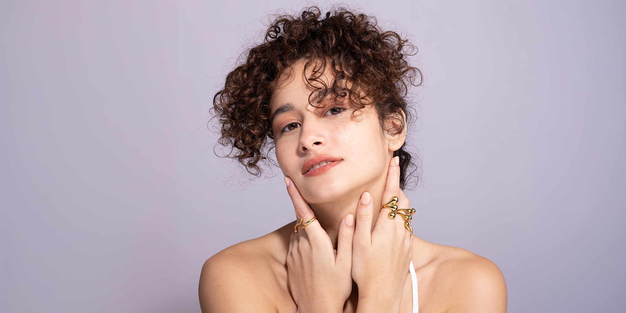 A women with curly hairs wearing ring stack.