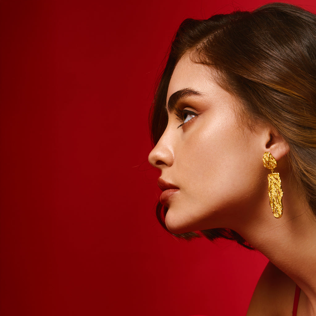 A woman wearing a 18K gold plated earring, showcasing its elegant design against her hair.