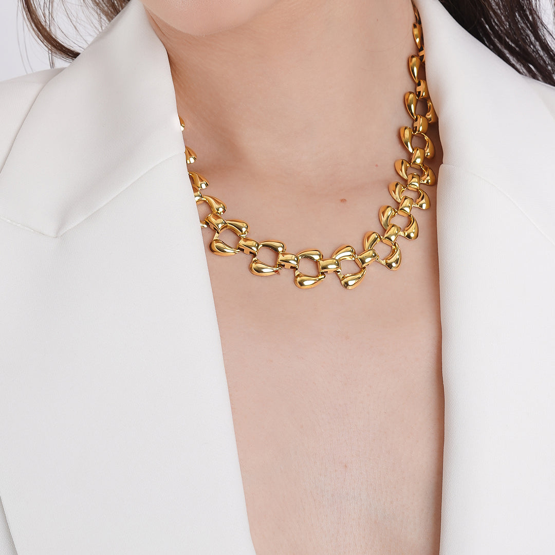 A woman wearing a 18K gold plated chain necklace, showcasing its elegant design against her white outfit.
