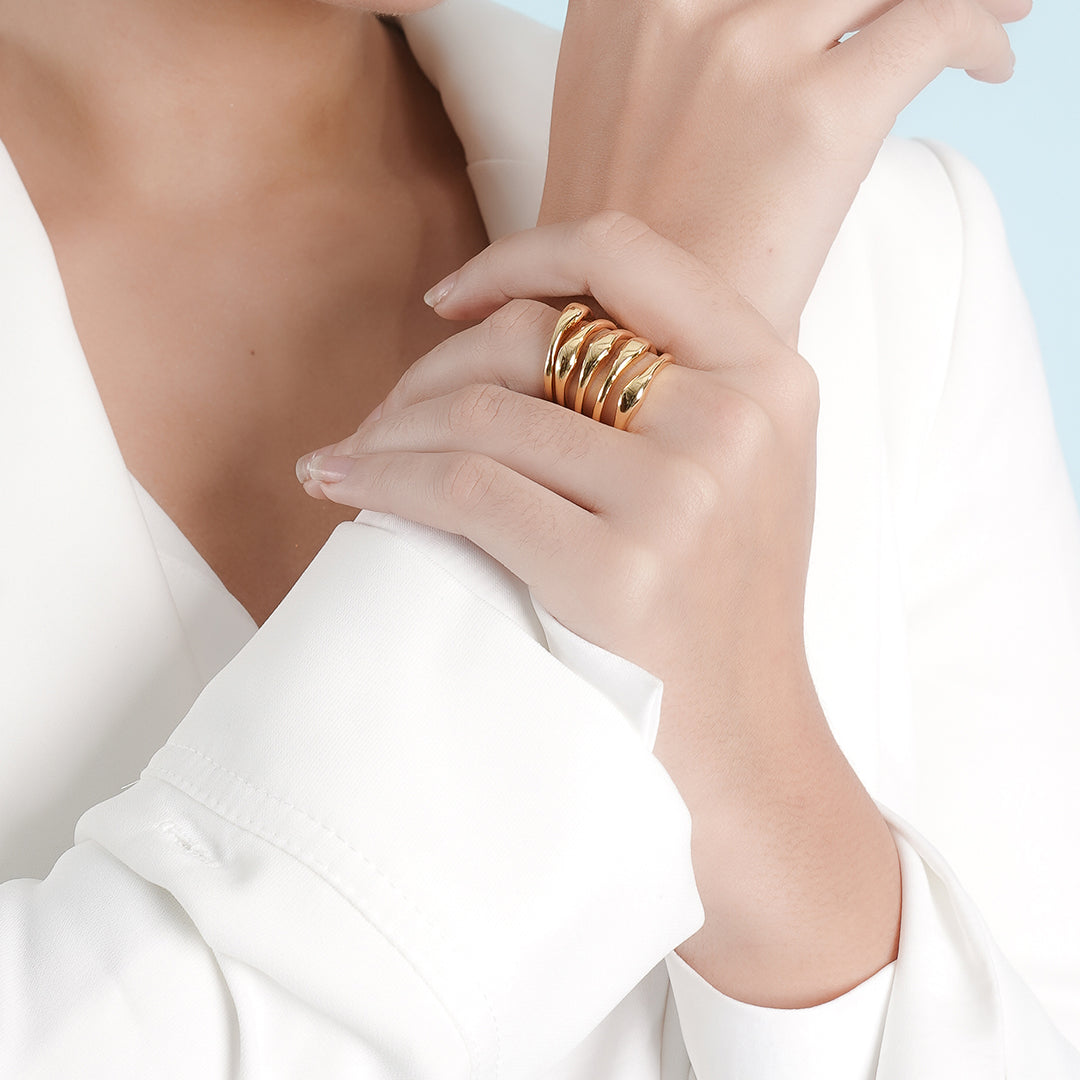 A woman in a white blazer, showcasing a 18K gold plated ring on her finger, exuding elegance and professionalism.