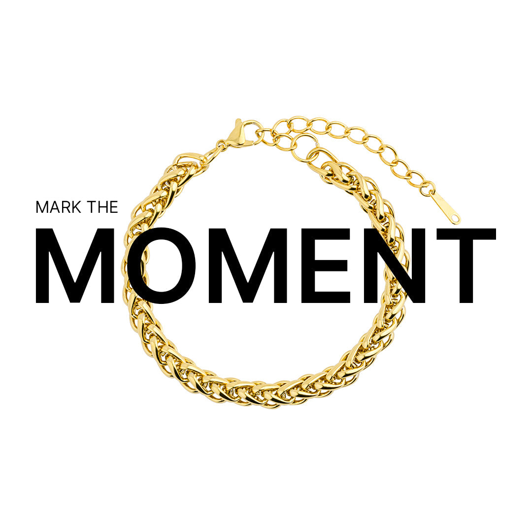 Elegant 18K gold-plated chain bracelet featuring a thick, twisted rope design and adjustable clasp, presented with the phrase "MARK THE MOMENT" where the bracelet curves around and overlays the bold word "MOMENT" on a clean white background.