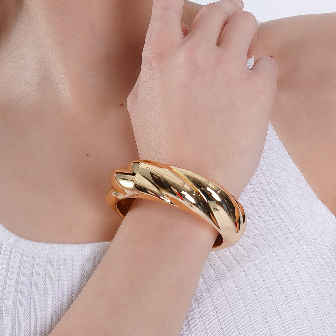 A woman showcasing a 18K gold plated bracelet elegantly worn on her wrist.