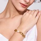 Gold bracelet with a pearl on a women's wrist against a white background