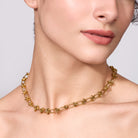 Gold chain necklace on a model against a neutral background