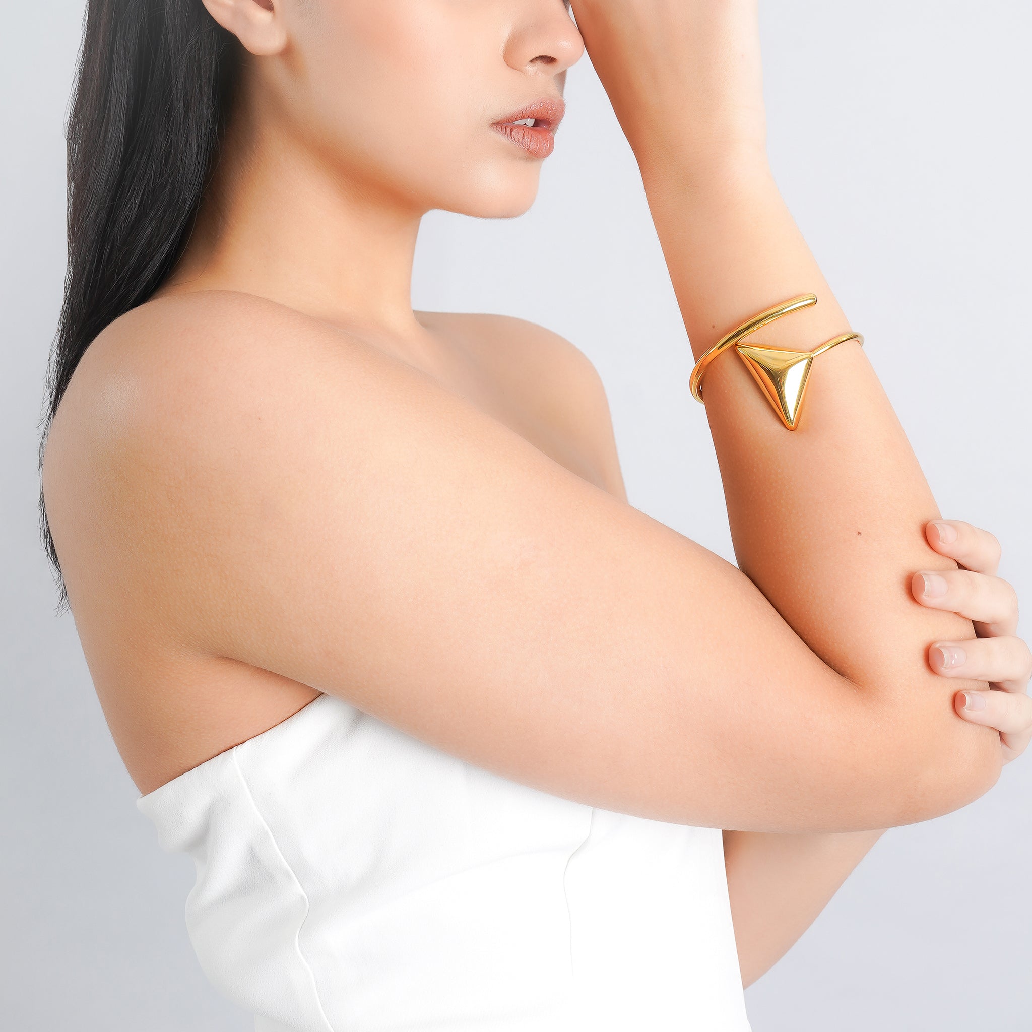 Model wearing a 18K gold-plated bracelet with a geometric triangular accent, adding a bold, minimalist touch to her elegant look.