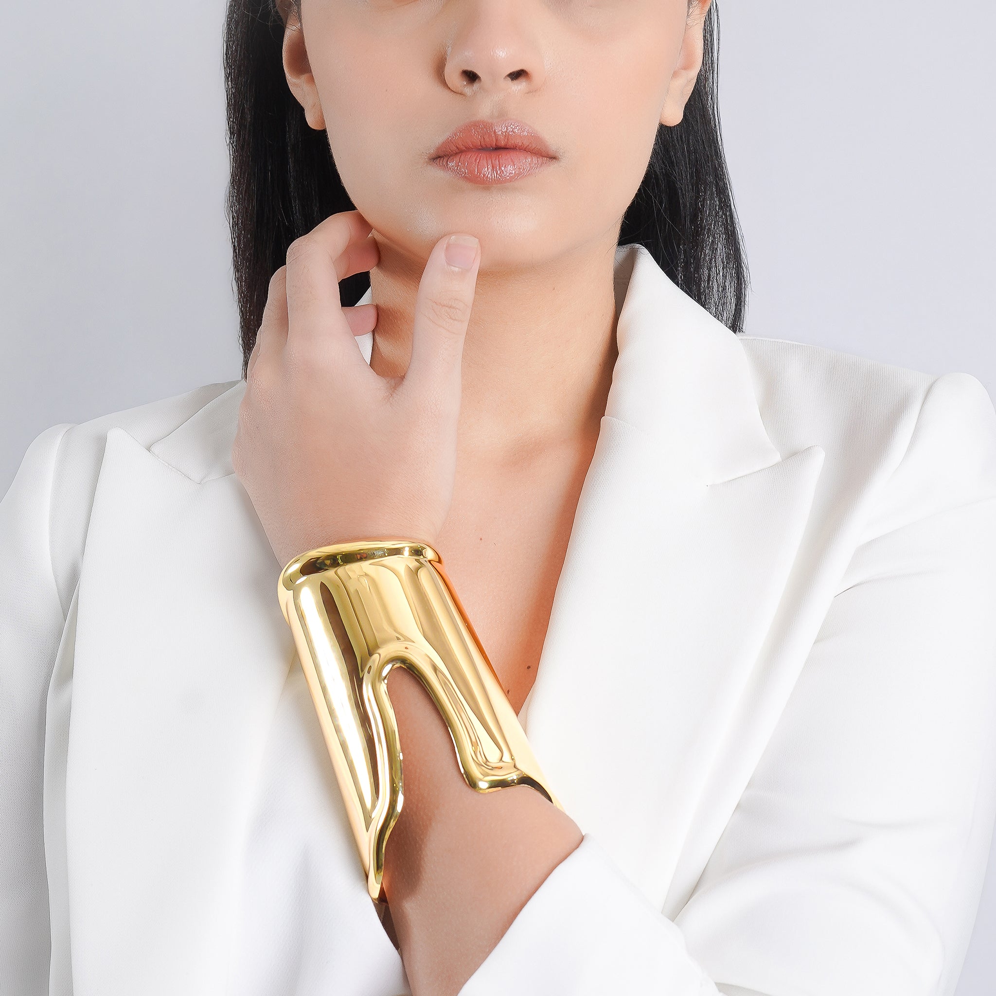 Model wearing an 18K gold-plated wide cuff bracelet with a bold, sculptural design, enhancing her minimal white outfit.