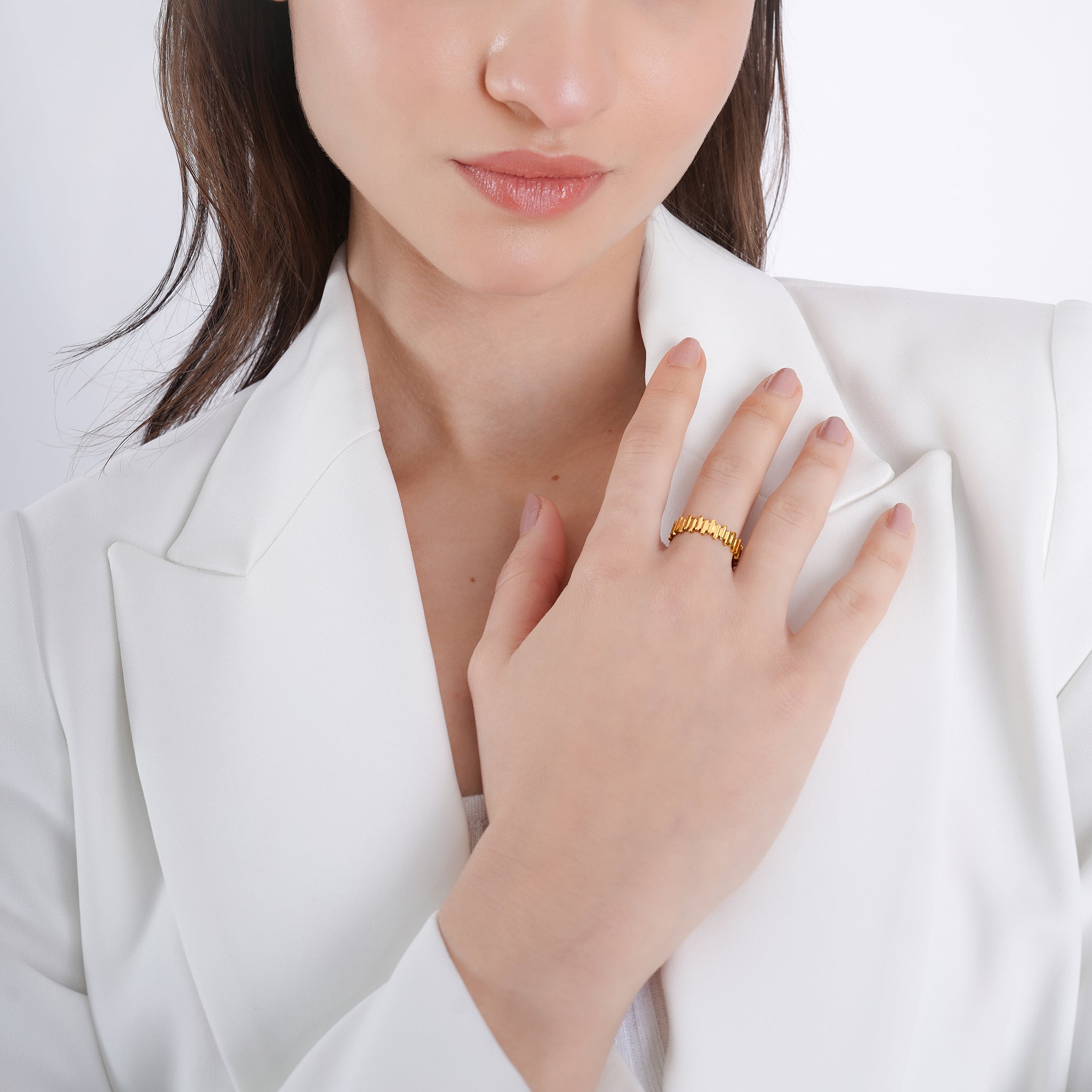 Model wearing an 18K gold-plated ring with a distinctive interlocking pattern, adding a refined, modern accent to her elegant outfit.