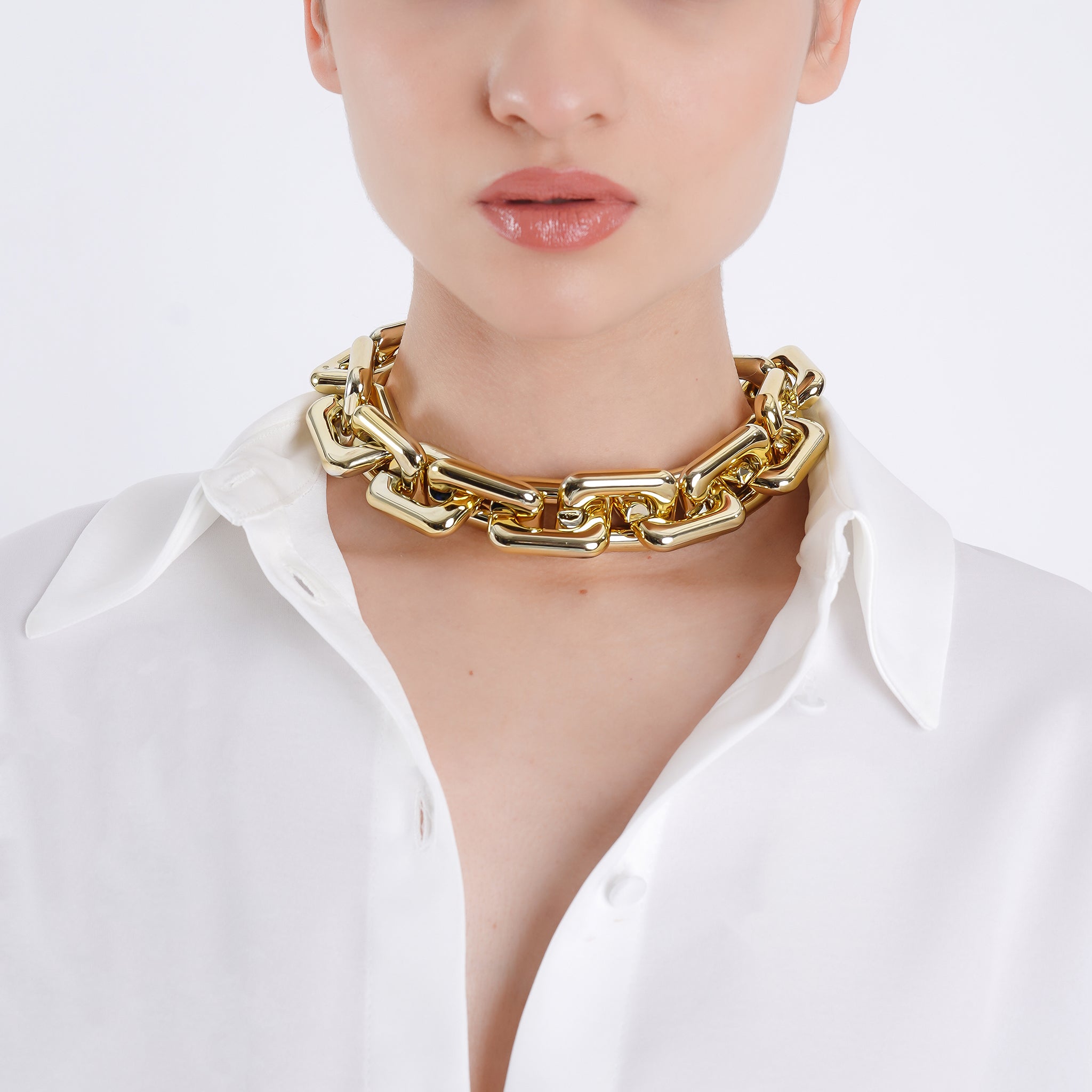 Model wearing an gold-plated chain-link necklace with bold, polished links, enhancing her sophisticated, modern look.