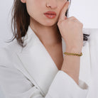 Model wearing an 18K gold-plated braided chain bracelet with a polished finish, adding a sophisticated touch to her elegant attire.