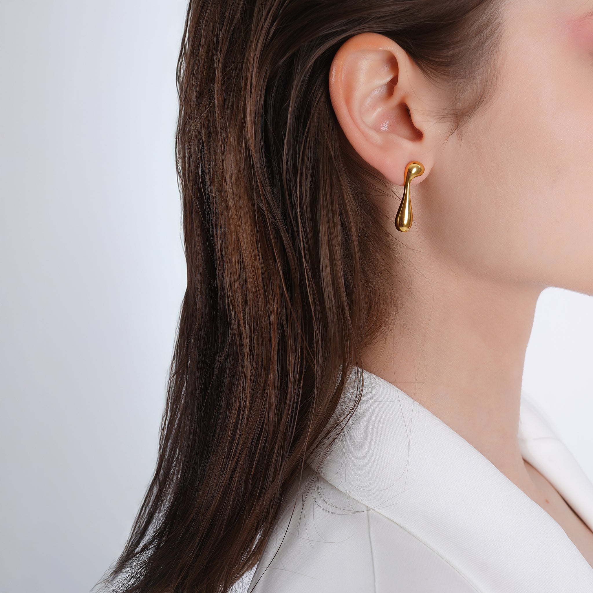 Model wearing 18K gold-plated abstract drop earrings with fluid, asymmetrical shapes, creating a bold, artistic accent.