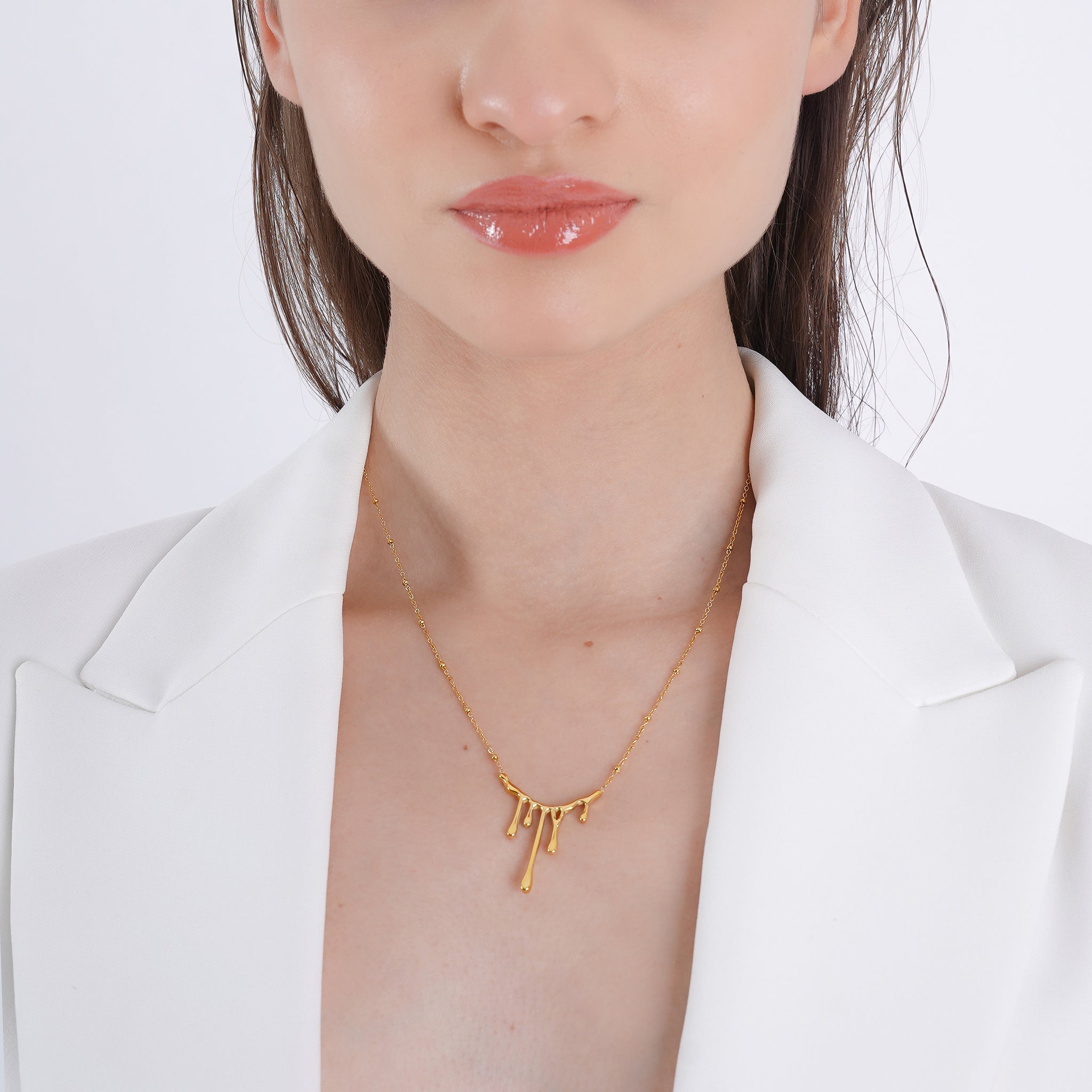 Model wearing an 18K gold-plated necklace with an abstract drip pendant, adding a modern and artistic touch to her refined look.
