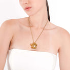 A model showcasing the 18K gold-plated floral necklace, with its central pearl resting elegantly against her upper chest, highlighting the intricate design.