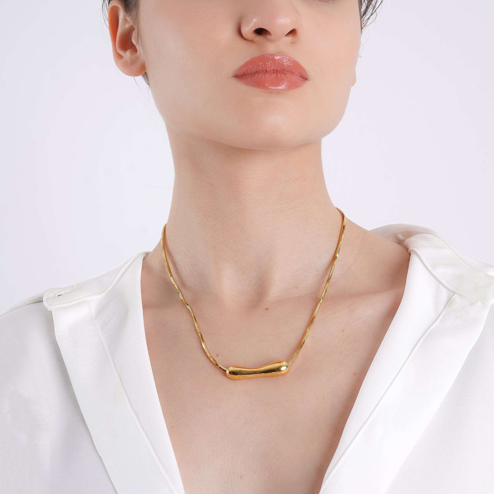 Woman wearing the 18K gold-plated necklace featuring a sleek curved bar pendant, adding a touch of minimal elegance to her outfit.