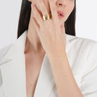 A model wearing the 18k gold-plated textured wide band ring, showcasing its bold and luxurious statement against a chic white outfit.