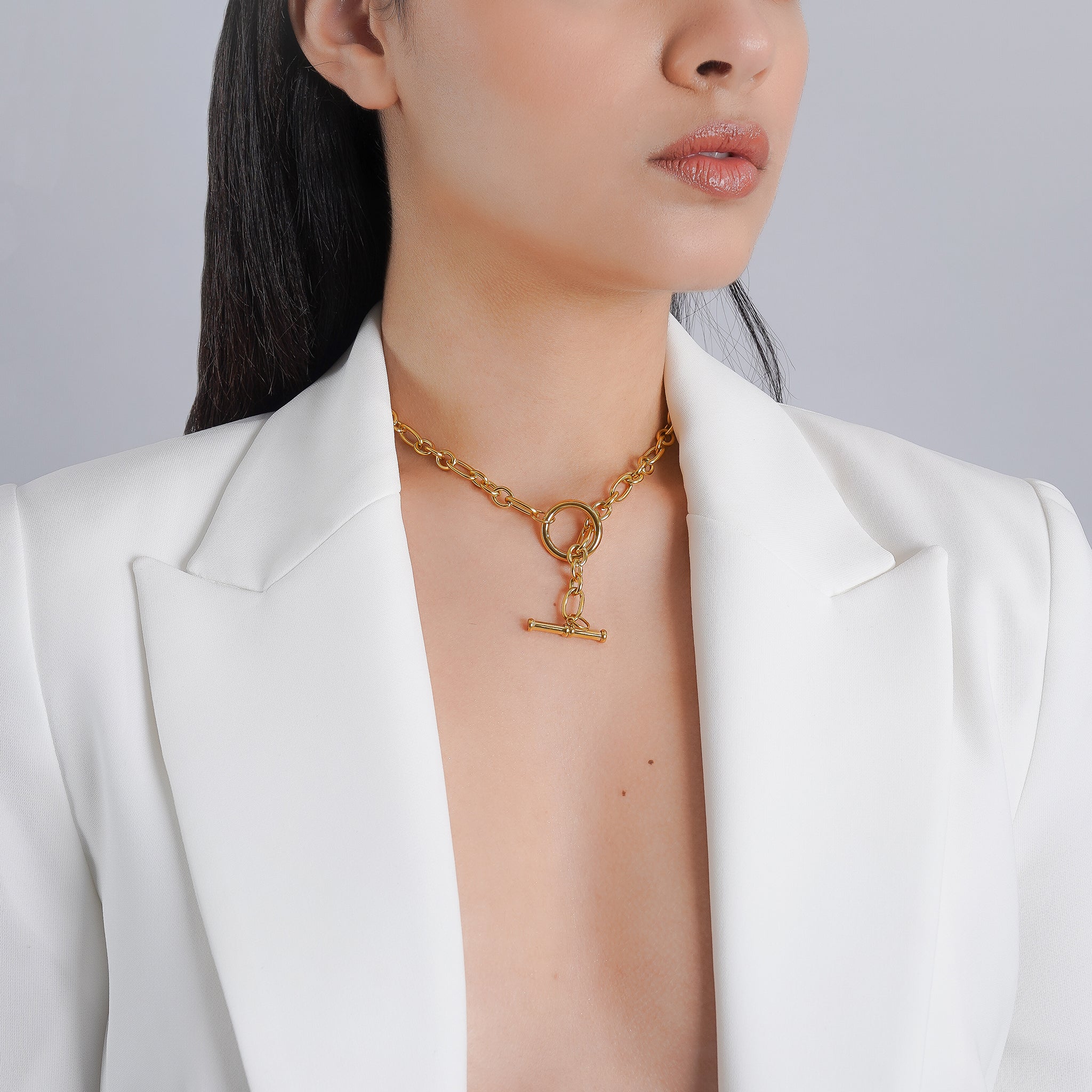 A model wearing the 18K gold-plated chain necklace with a toggle clasp resting elegantly on her neck, styled over a white blazer for a chic, modern look.