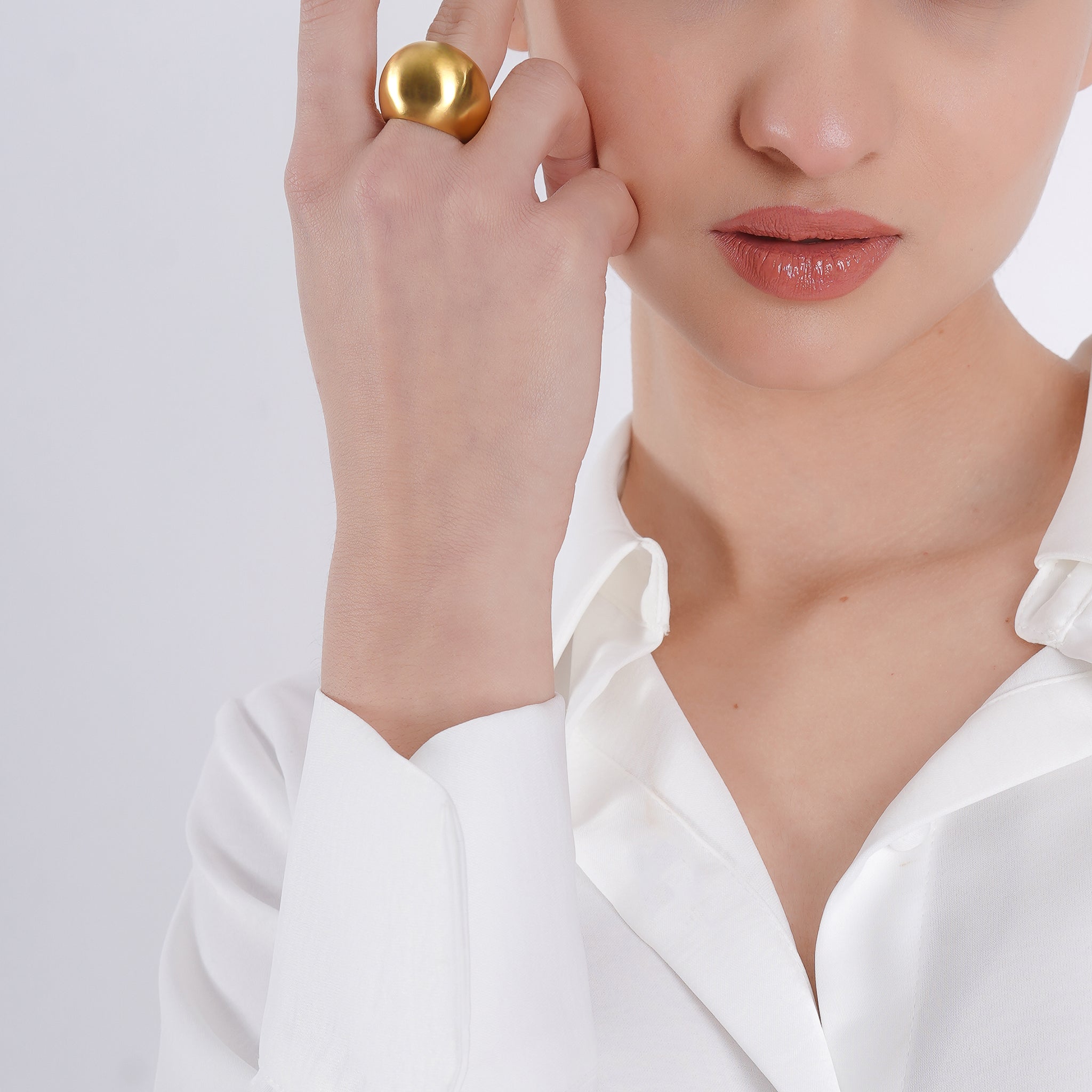 Model wearing the 18K gold-plated dome shaped statement ring with a brushed finish, styled with a white shirt, emphasizing its bold elegance and minimalist sophistication.  