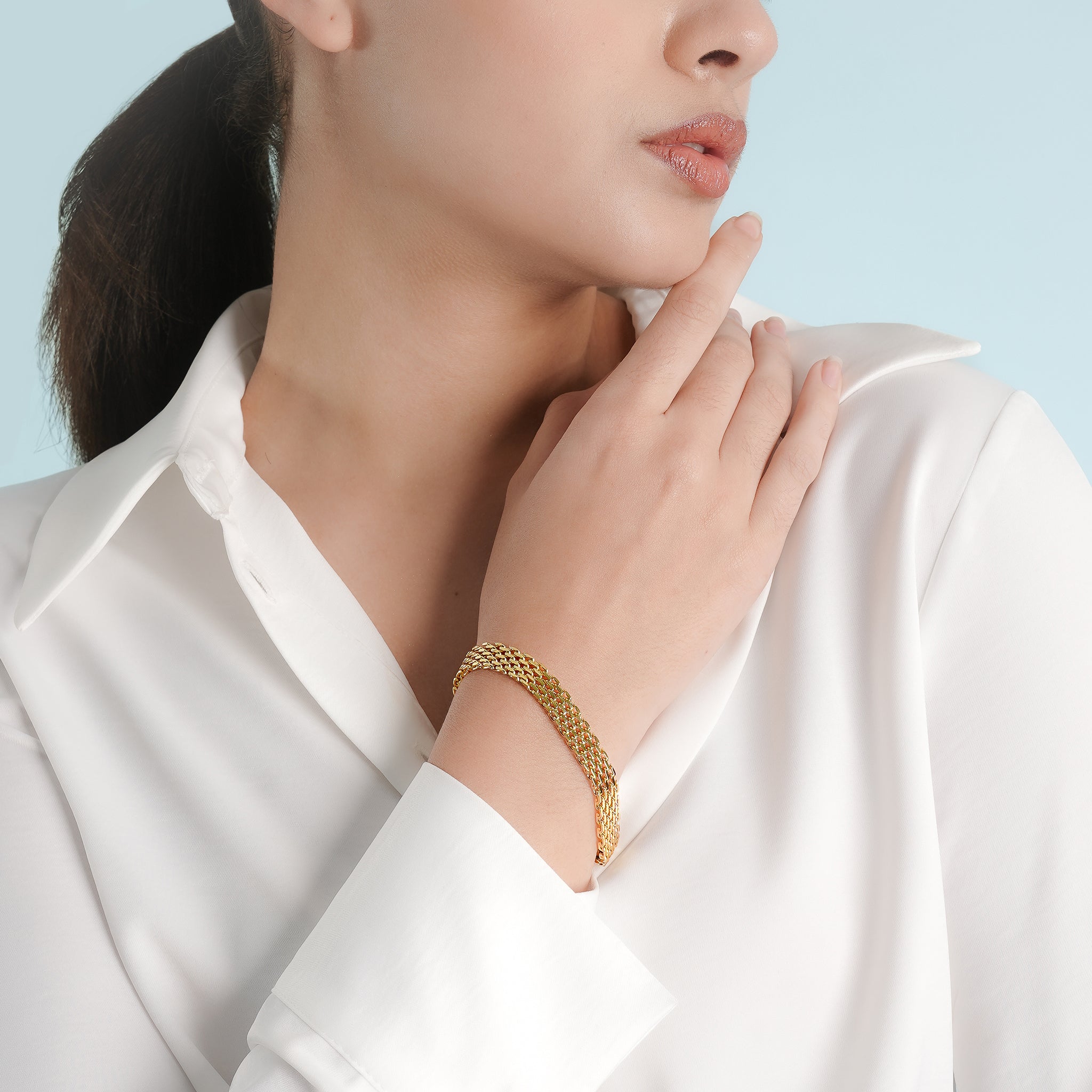 Model wearing the 18K gold-plated multi-strand bracelet, featuring delicate interwoven links for a textured finish, styled with a white shirt to accentuate its elegant and refined look.