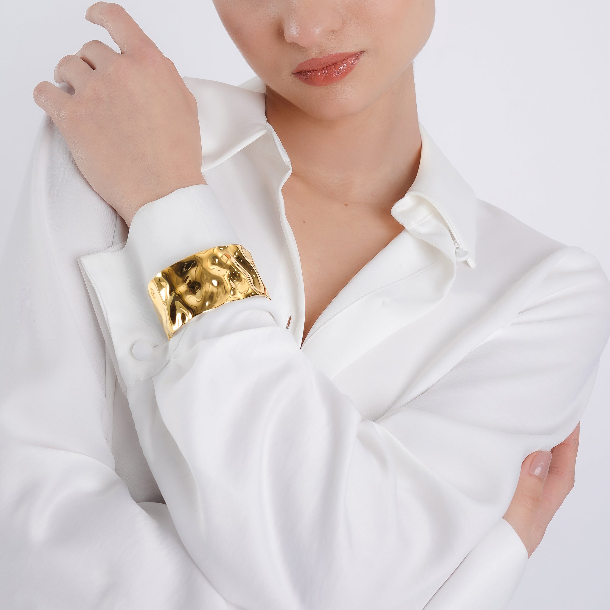 Model wearing the 18K gold-plated wavy cuff bracelet, styled with a crisp white shirt, showcasing its sculptural elegance and contemporary flair.