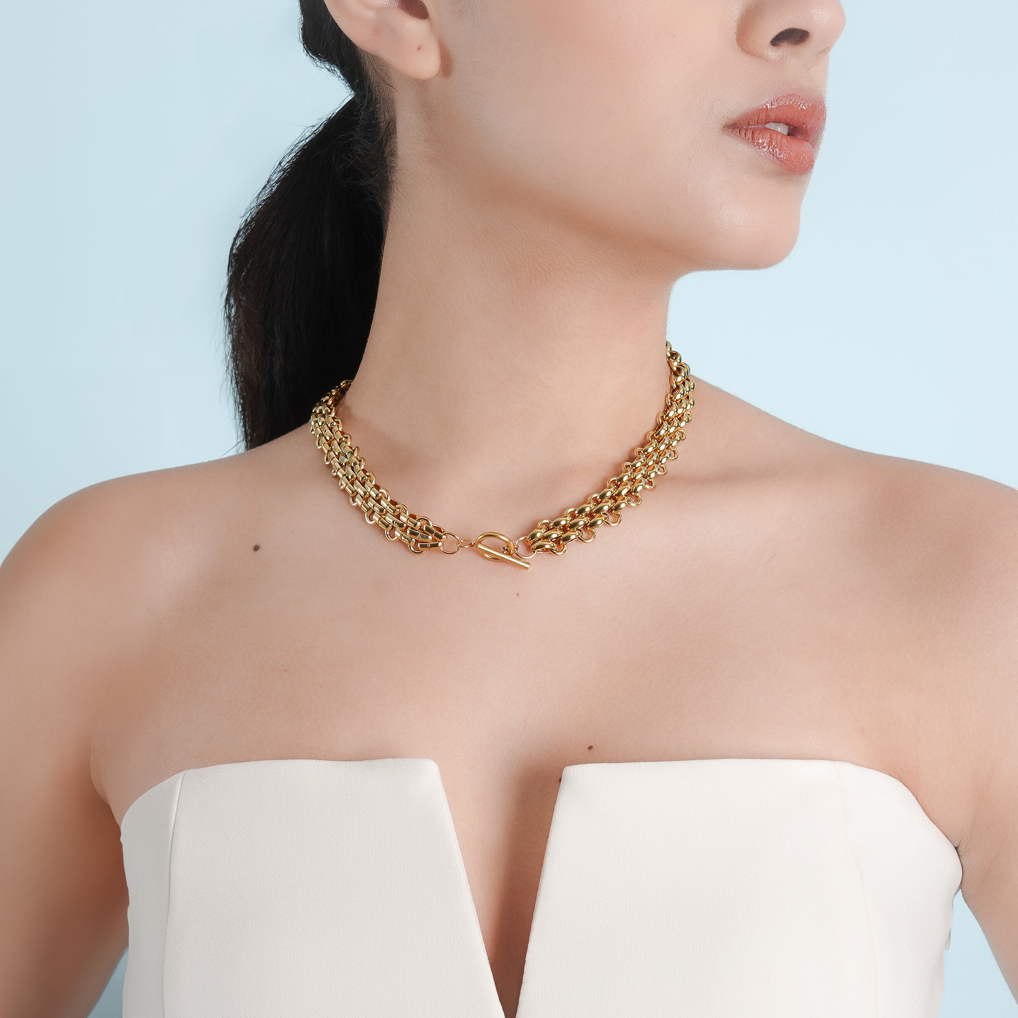 Model wearing the 18K gold-plated woven chain necklace with a toggle clasp, paired with a white tube top, highlighting its sophisticated texture and bold elegance.