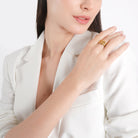 Model wearing the 18K gold-plated openwork ring with interwoven teardrop motifs, styled with a white blazer, highlighting its artistic flair and distinctive charm.