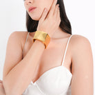 Model wearing the 18K gold-plated wide cuff bracelet with a minimal white outfit, highlighting its sleek, polished finish and bold design, making it the perfect statement accessory for a refined, contemporary look.