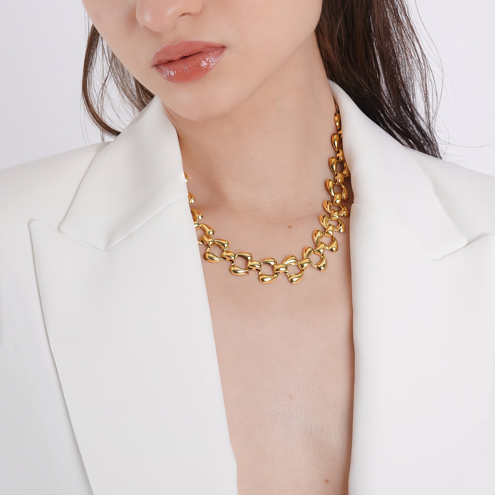 Model wearing the 18K gold-plated interlocking leaf link necklace, styled with a white blazer, showcasing its statement appeal and luxurious finish.