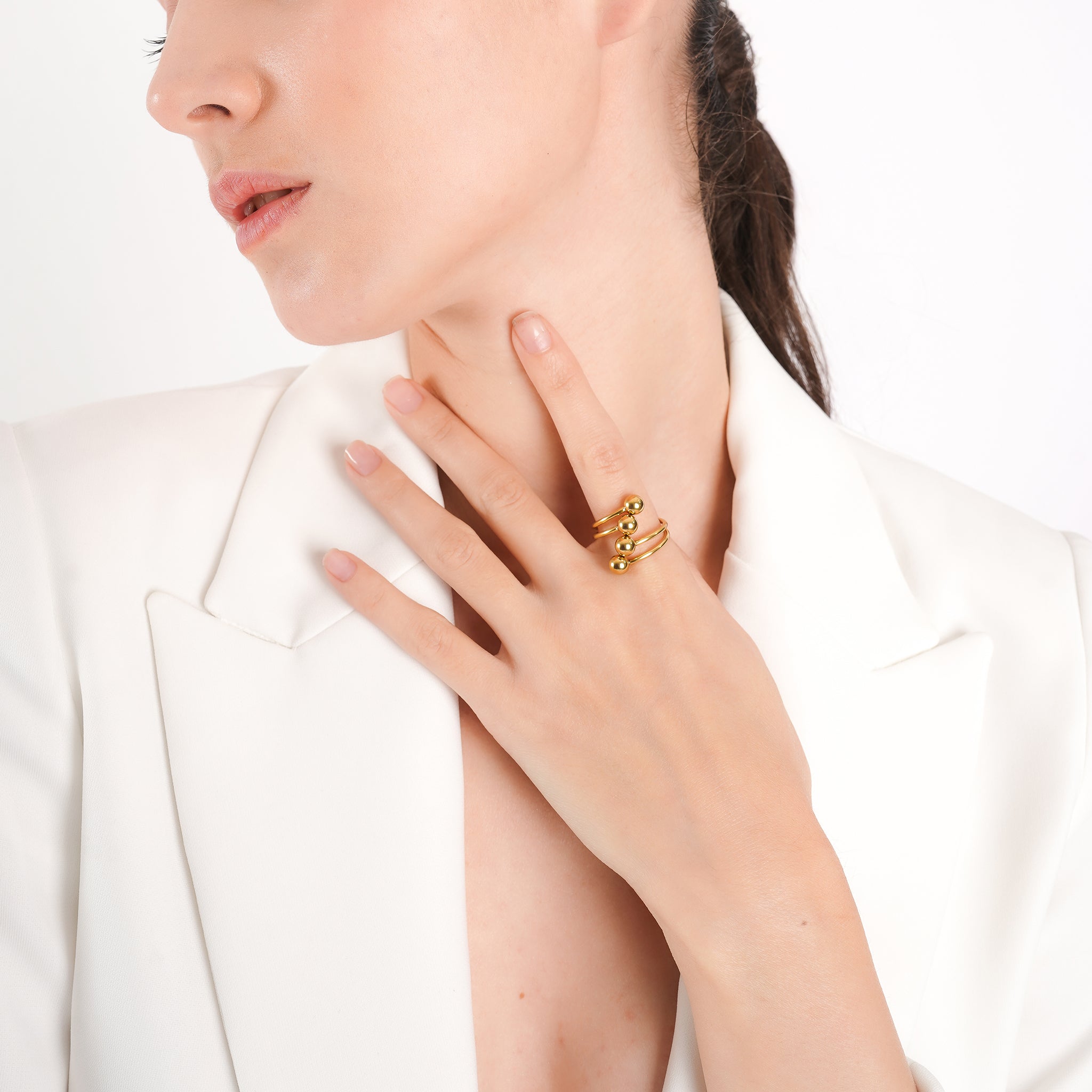 Model wearing the 18K gold-plated multi-band ring with prominent spherical accents, paired with a white blazer, emphasizing its modern elegance and statement appeal.