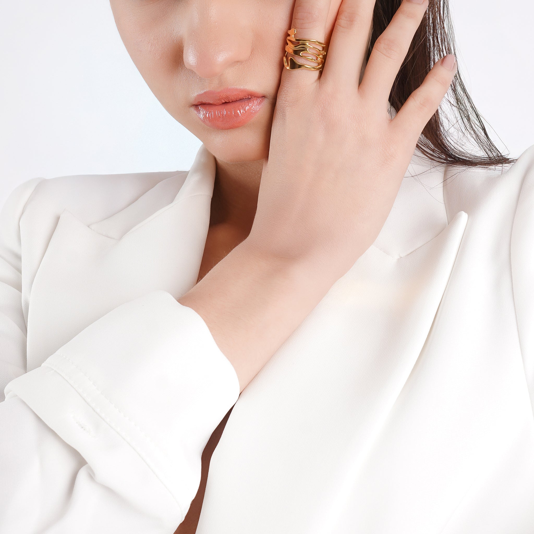 Model wearing an 18K gold-plated abstract open ring with flowing wave-like details, complementing her white blazer for a refined, artistic look.