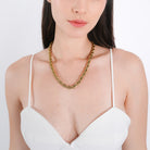 Model wearing a 18K gold-plated rope chain necklace with a twisted design, styled elegantly over a white V-neck top.