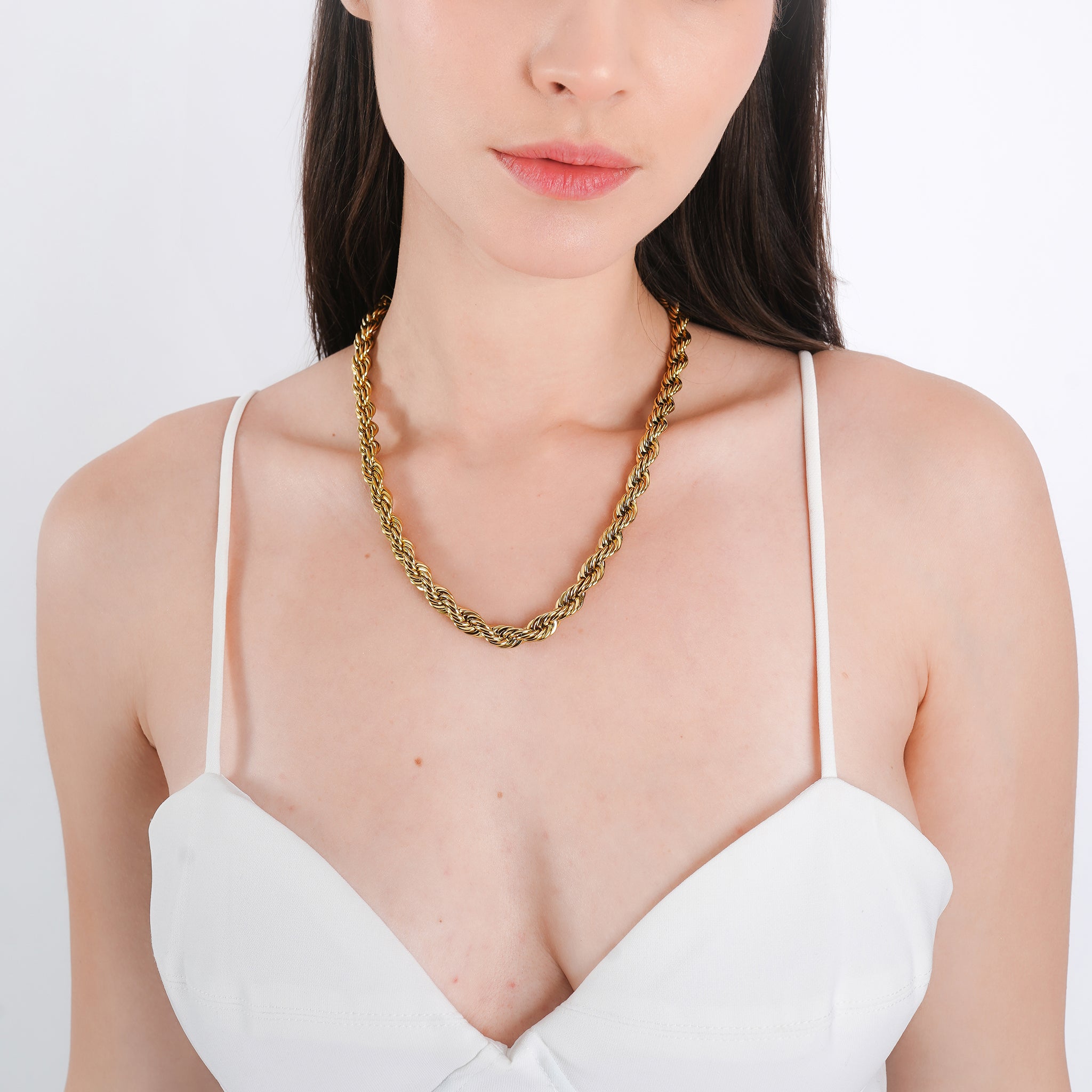 Model wearing a 18K gold-plated rope chain necklace with a twisted design, styled elegantly over a white V-neck top.