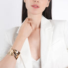 Model wearing an 18K gold-plated abstract cuff bracelet with a wavy, reflective design, paired with a white blazer for an elegant statement.