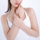 Model showcasing an 18K gold-plated abstract wave ring with smooth, flowing curves, worn on the index finger, paired with a white minimalist outfit.