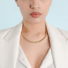 Model wearing an 18K gold snake chain necklace paired with a white blazer, highlighting its minimalist elegance on the neckline.