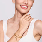 Woman wearing a gold bracelet on a plain background