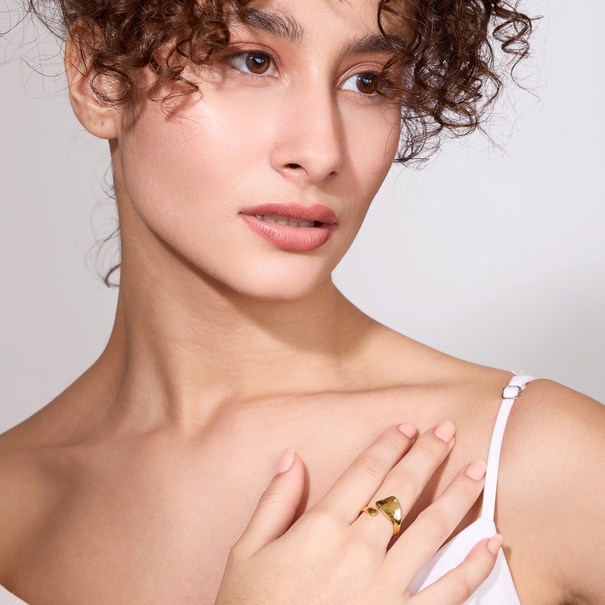 Woman wearing a gold ring on a plain background