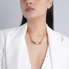 The model elegantly showcases the 18K gold-plated crescent pendant necklace, resting gracefully against the collarbone, complementing a white blazer for a refined and sophisticated look.