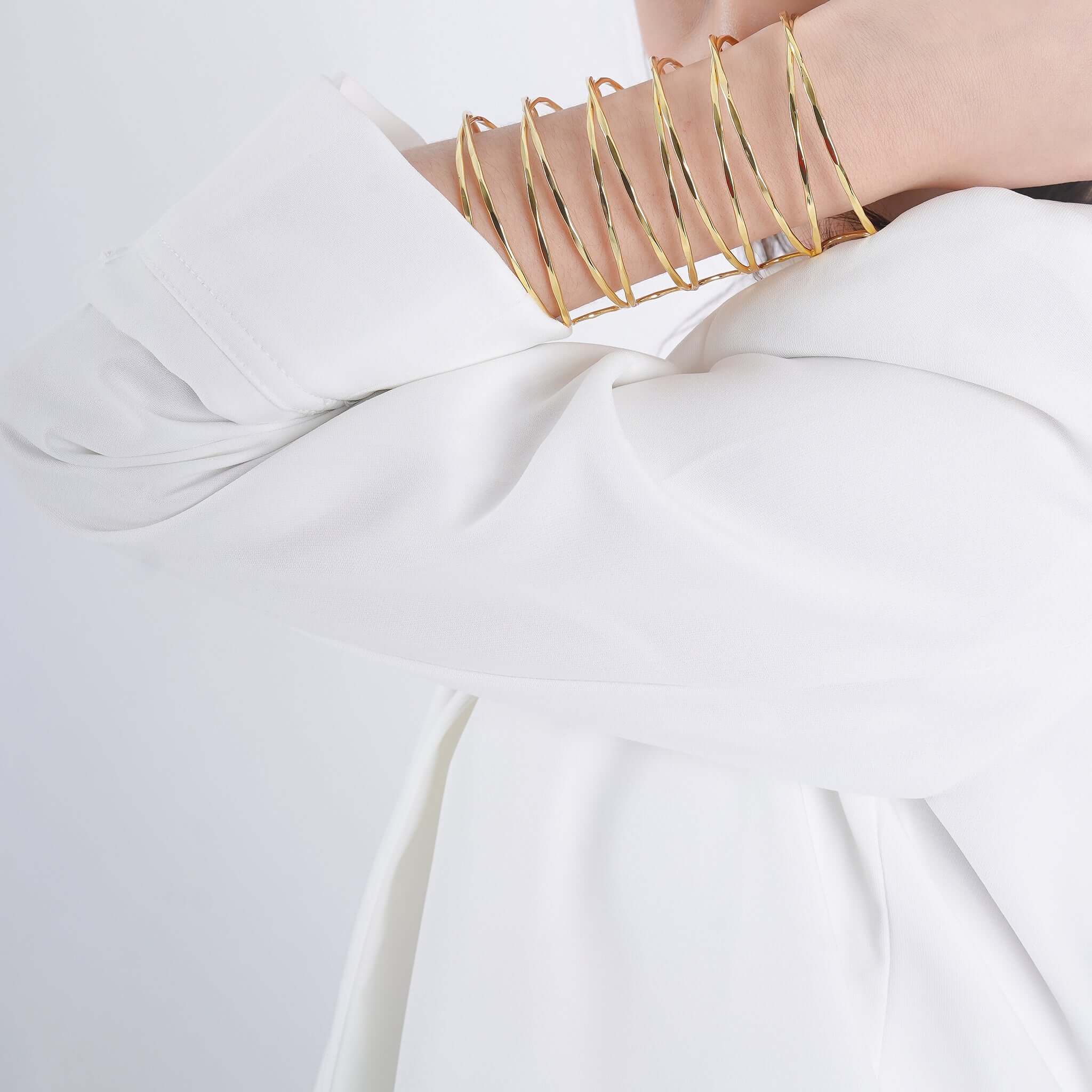 Model wearing an 18K gold-plated multi-loop cuff bracelet, elegantly styled over a white sleeve, highlighting its layered open-wire loops and sophisticated aesthetic.