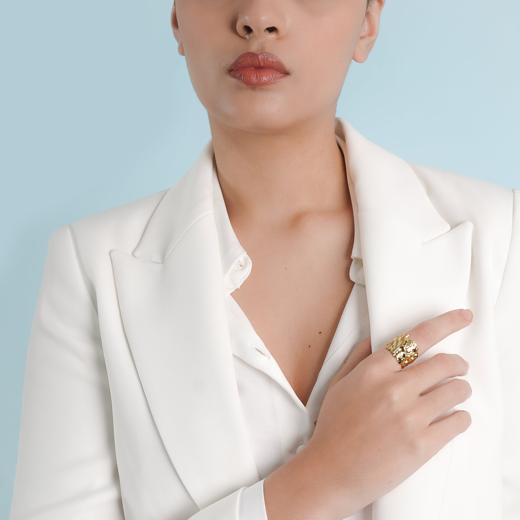 A model showcasing the textured 18K gold ring, elegantly styled with a white blazer for a refined and sophisticated look.