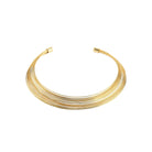 A sleek, multi-layered gold choker necklace composed of delicate, closely arranged wires creating a smooth, polished finish.