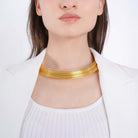 A model wearing a gold choker necklace featuring multiple, fine layered strands that rest comfortably around the neck.