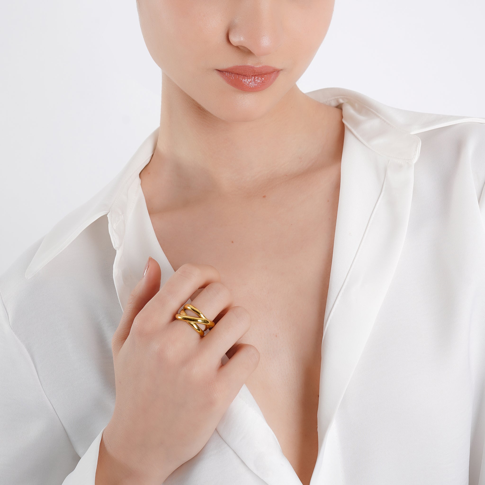 A model wearing the 18K gold-plated intertwined ring on the index finger, paired with a white silk blouse, enhancing its luxurious and sophisticated appeal.