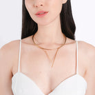 A woman in a white sleeveless top elegantly displays the 18K gold-plated Y-shape collar necklace, highlighting its refined and minimalist design that rests gracefully on her neckline.