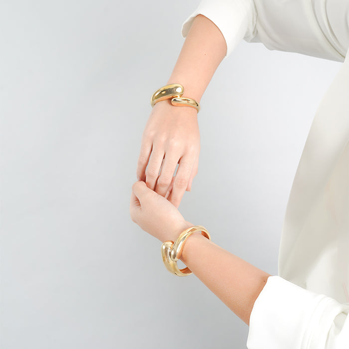 18K gold-plated sculptural cuff bracelet featuring a bold, fluid design with an open structure. A statement piece that adds modern elegance to any outfit.