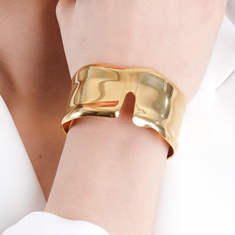 Sculptural 18K gold-plated cuff bracelet with an organic, fluid shape and a modern open-front design. A bold statement piece that combines artistry with elegance.